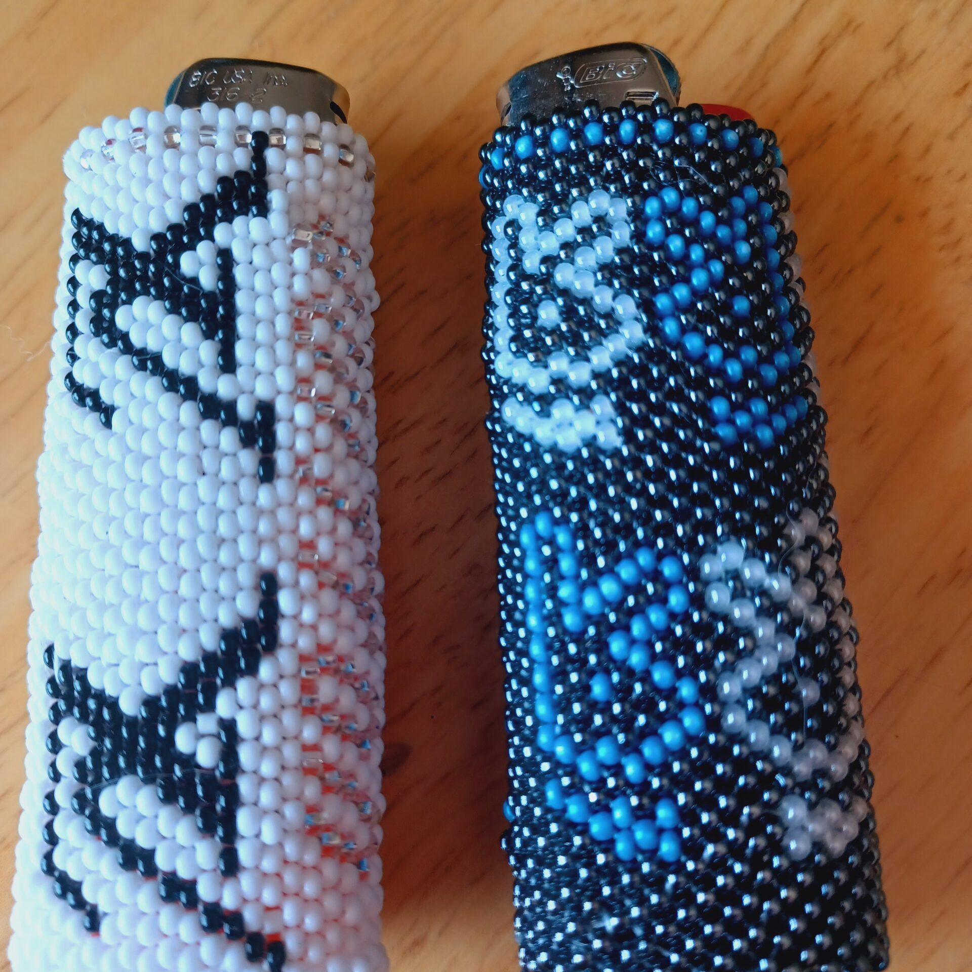 Amanda Lepine -Two Beaded Lighter Cases, one black with blue writing, the second white with black writing